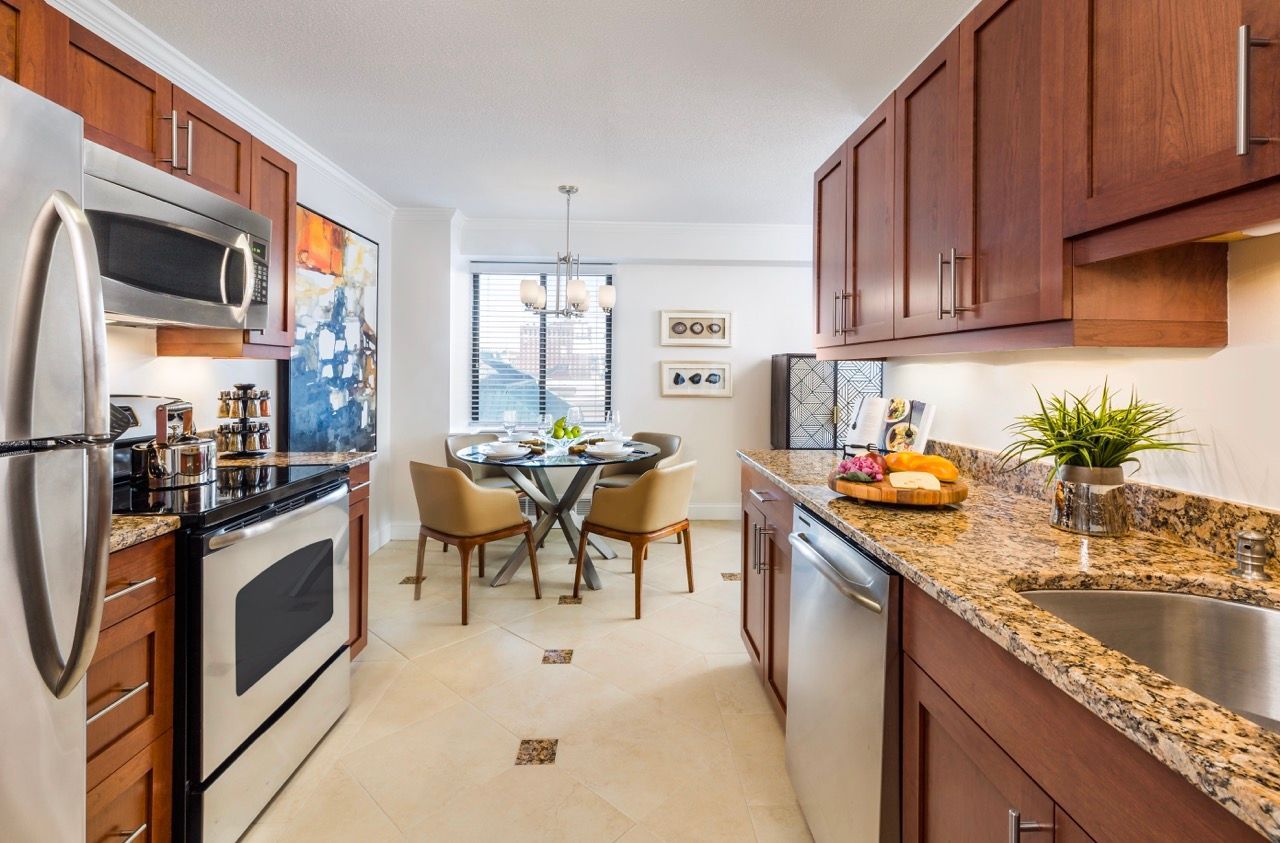 Modern kitchen with stainless steel appliances and granite countertops, adjacent dining area.