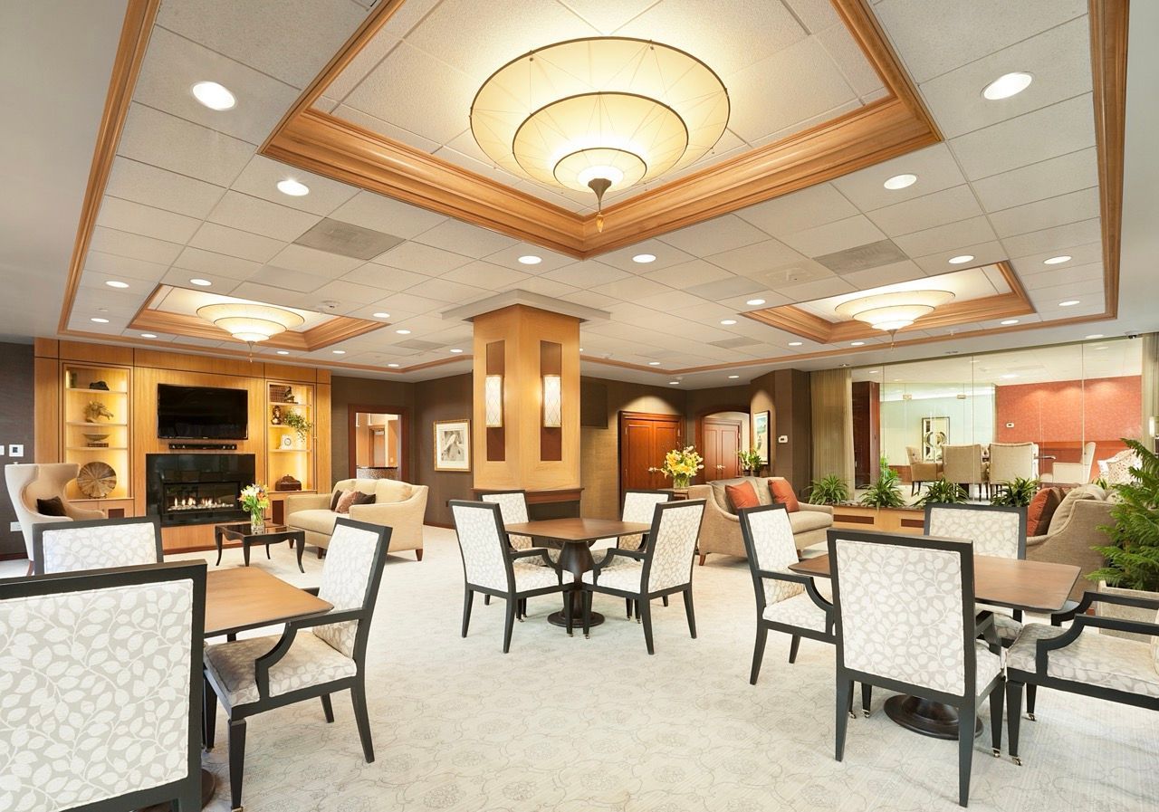 Interior of a spacious resident lounge with sofas, tables, built-in shelves, and a fireplace.