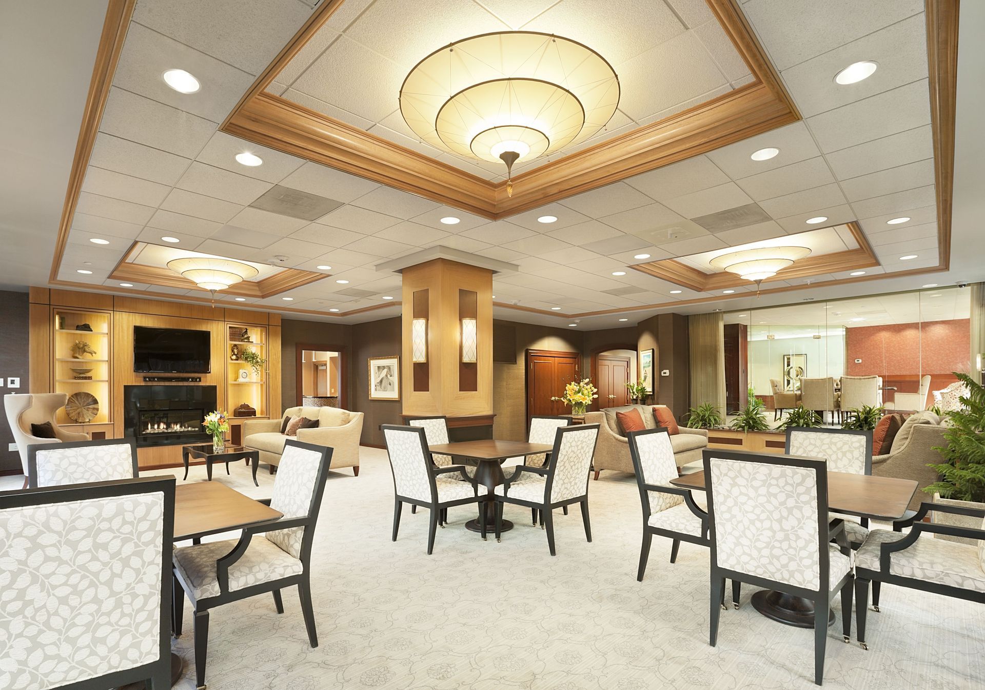 Interior of a spacious resident lounge with sofas, tables, built-in shelves, and a fireplace.