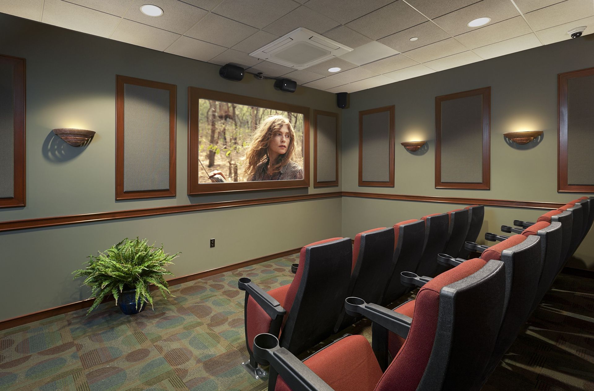 Indoor community theater room with red upholstered seats and wall panels.