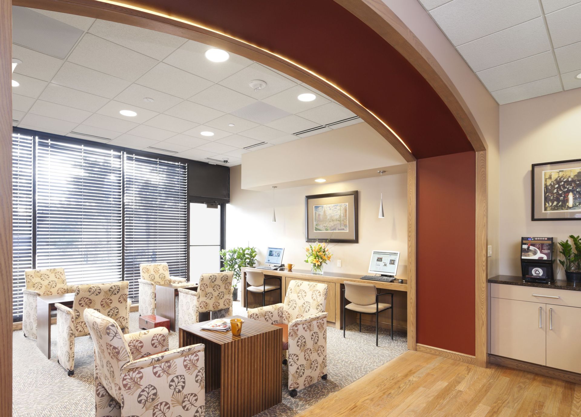 Interior community lounge with curved archway, patterned chairs, and computer stations.