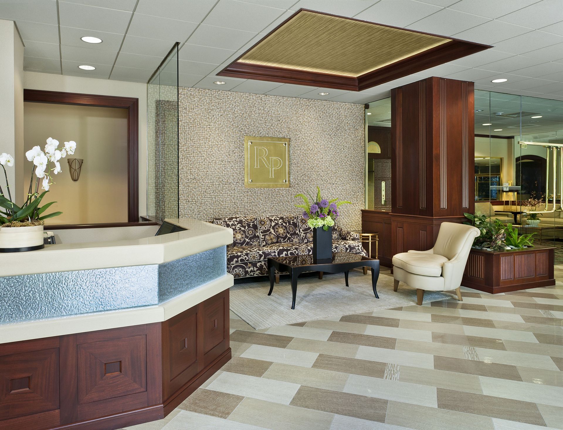 Modern apartment lobby with reception desk, seating, and mosaic wall.