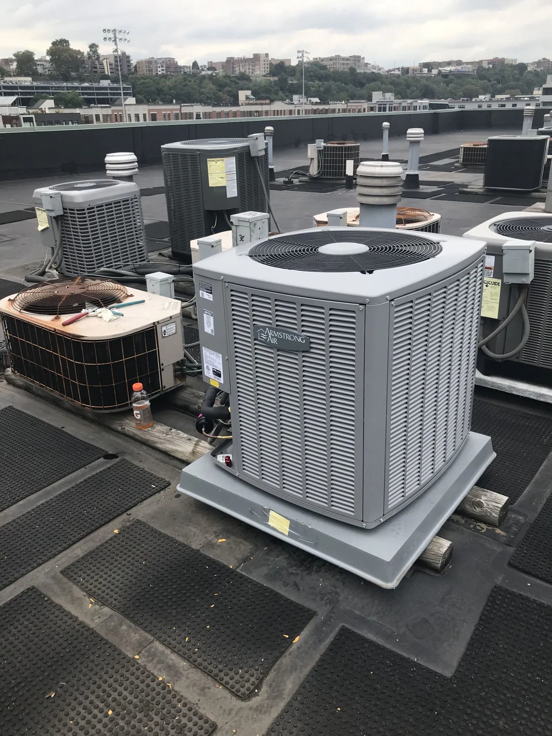 Air conditioning units on a rooftop. Gray and metal units in a commercial setting. Cloudy sky in the background.