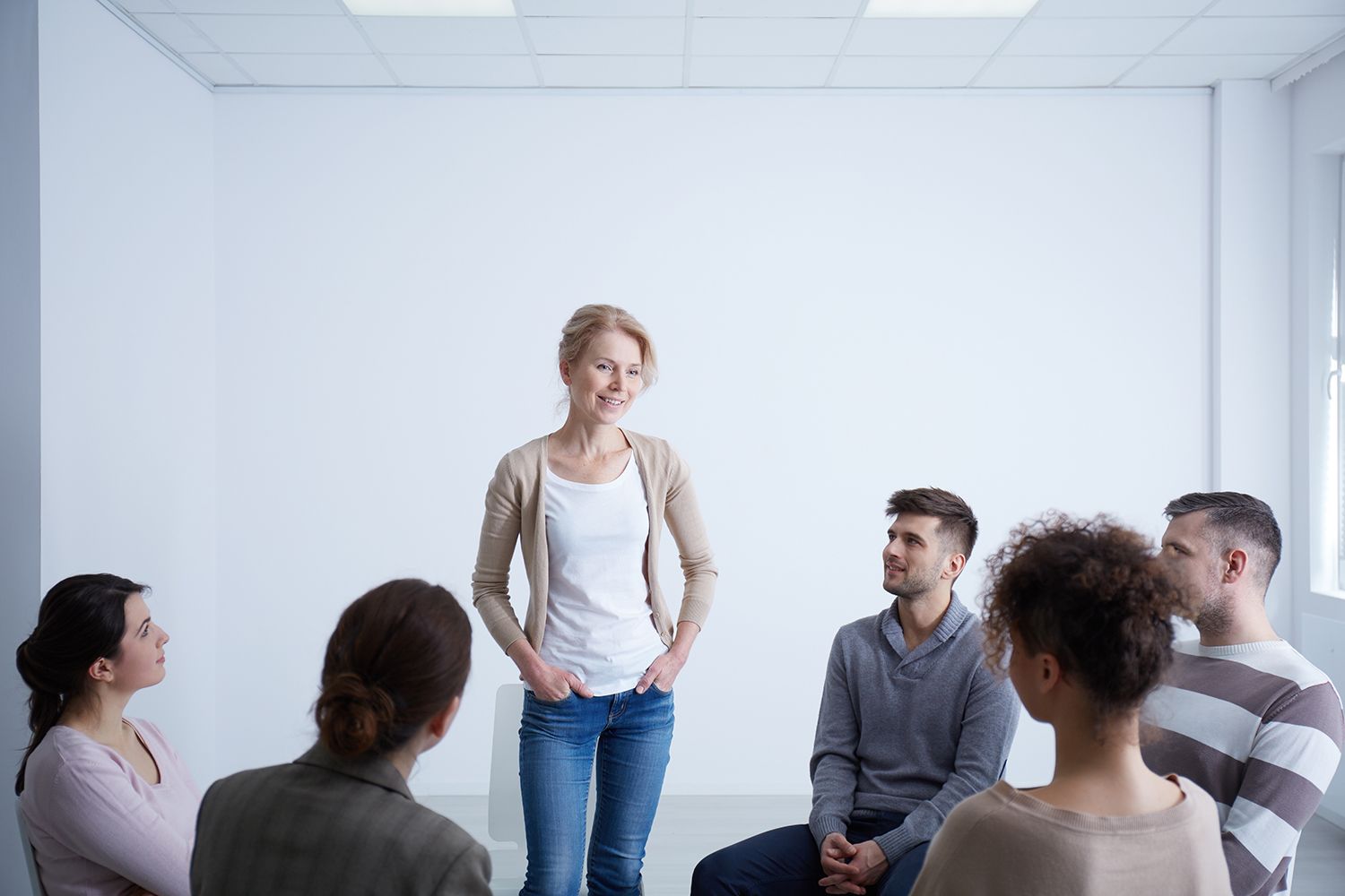Woman speaking to a seated group in a bright meeting room