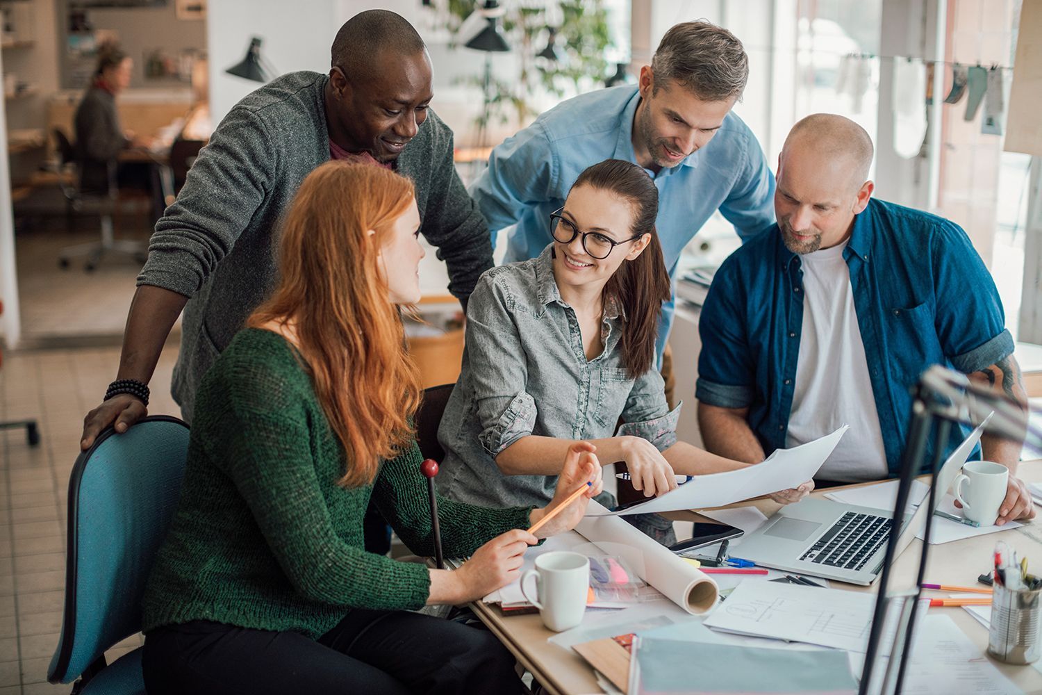 Team collaborating around a laptop and papers in a bright office meeting room