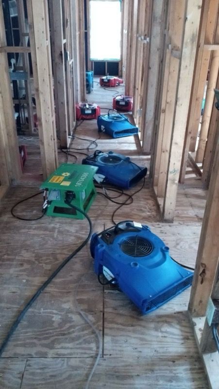 Fans and dehumidifiers drying a wooden hallway during construction.