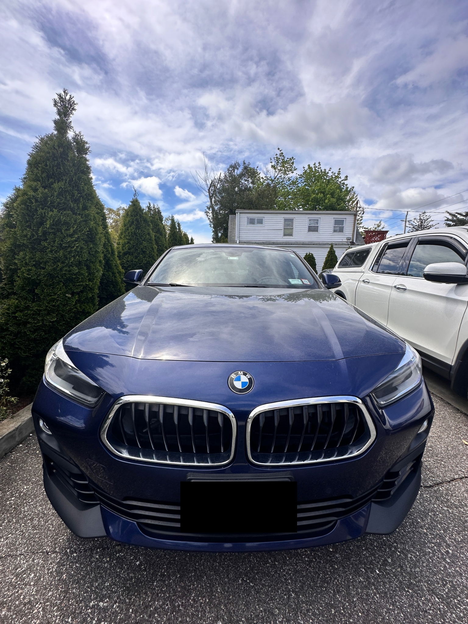 Dark blue BMW SUV parked in front of a house on a cloudy day. | Road Ready