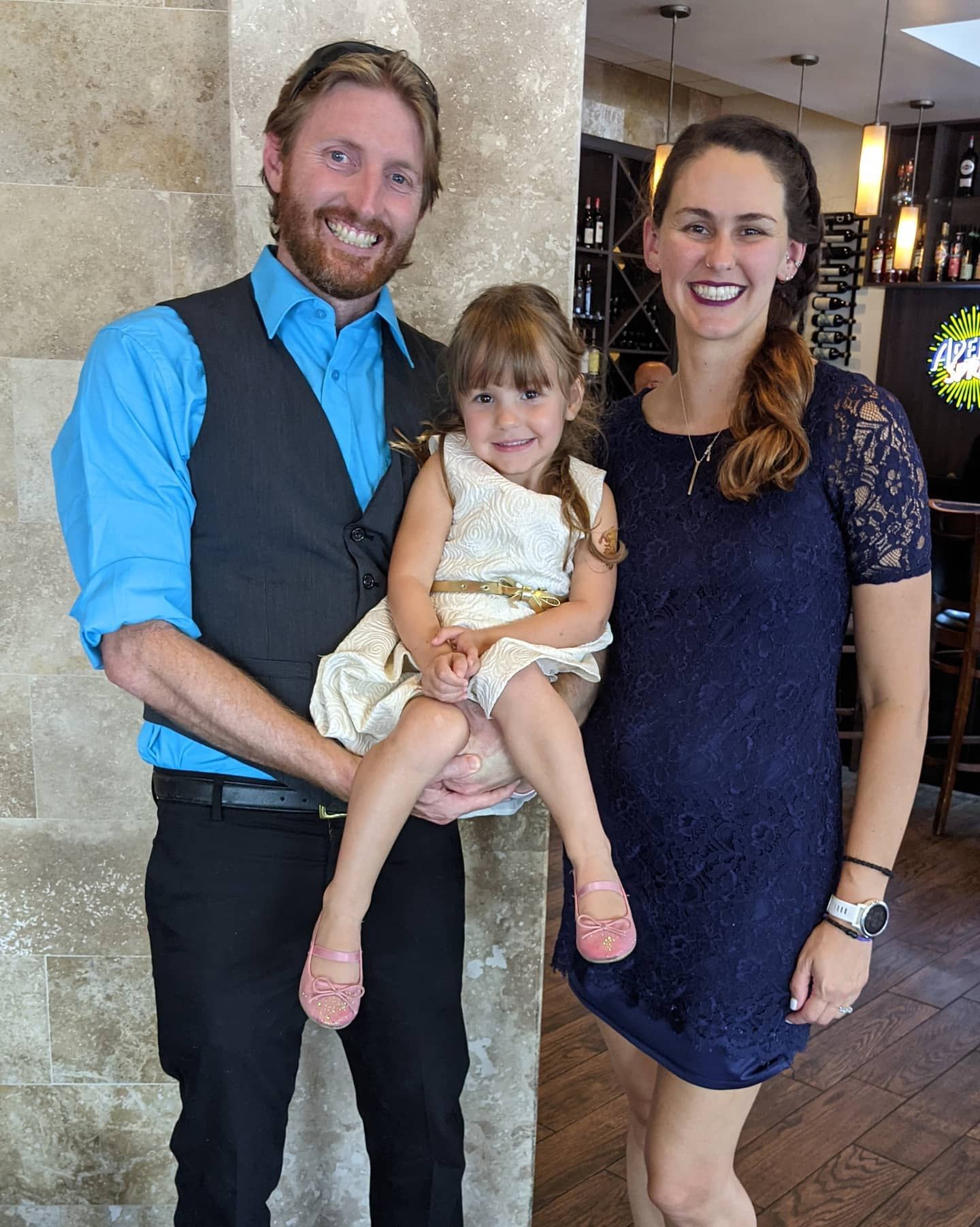 A man and woman holding a little girl in their arms