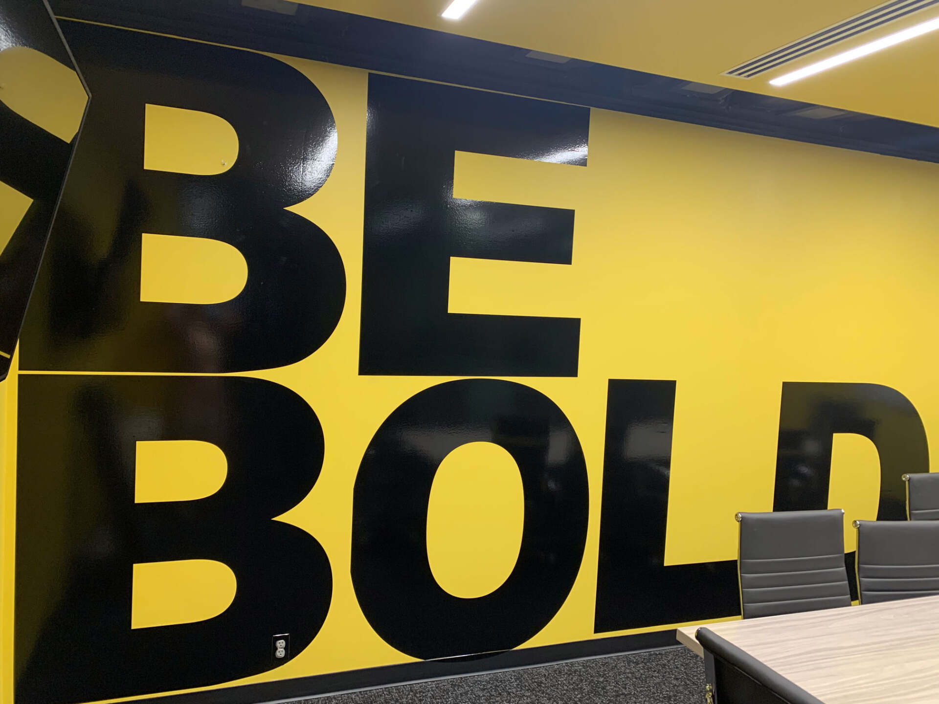 A yellow wall with black letters that say be bold