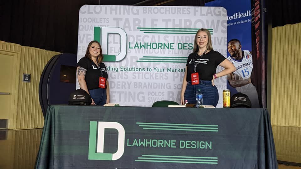Two women are standing behind a table with a sign that says lawhorne design.