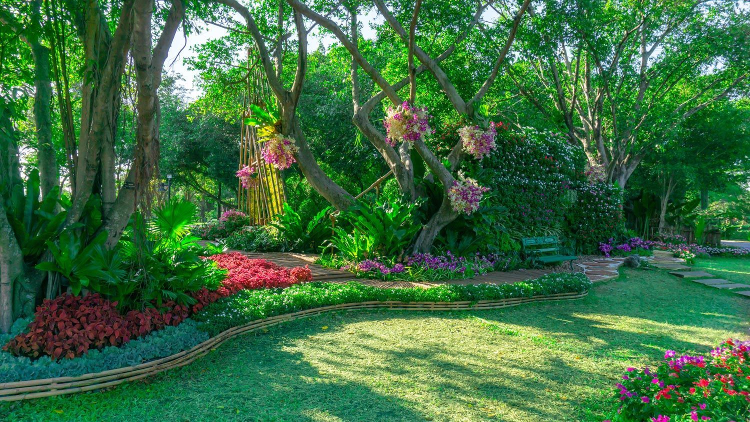 Lush garden with green trees, pink flowers, and a sunlit lawn Lush garden with green trees, pink flowers, and a sunlit lawn