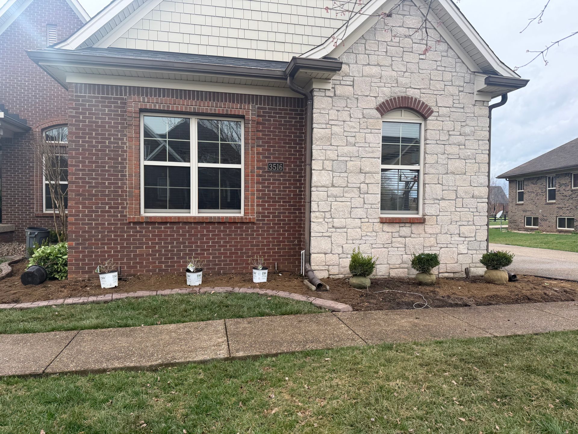 Brick and stone house exterior with front window, walkway, and small landscaped yard