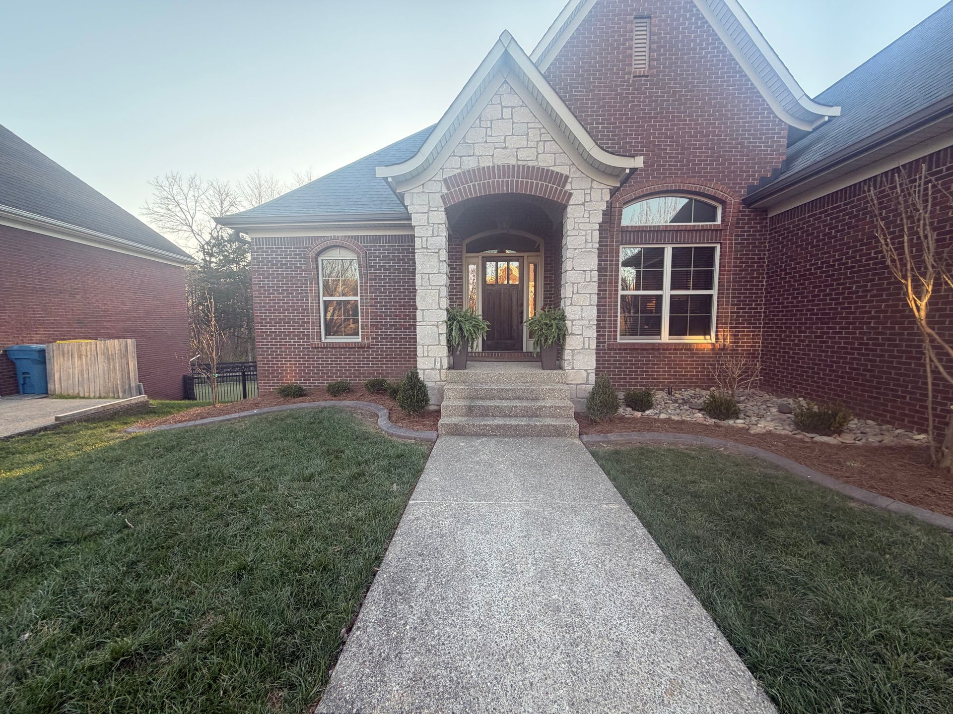 Brick house with arched entryway and front walkway at sunset