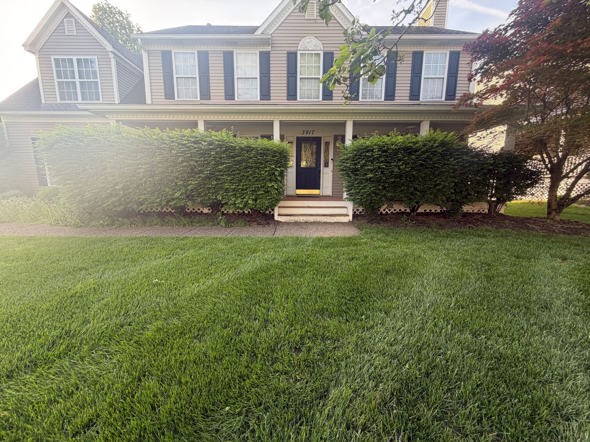 Two-story suburban house with gray shutters, brick walkway, and a green front lawn