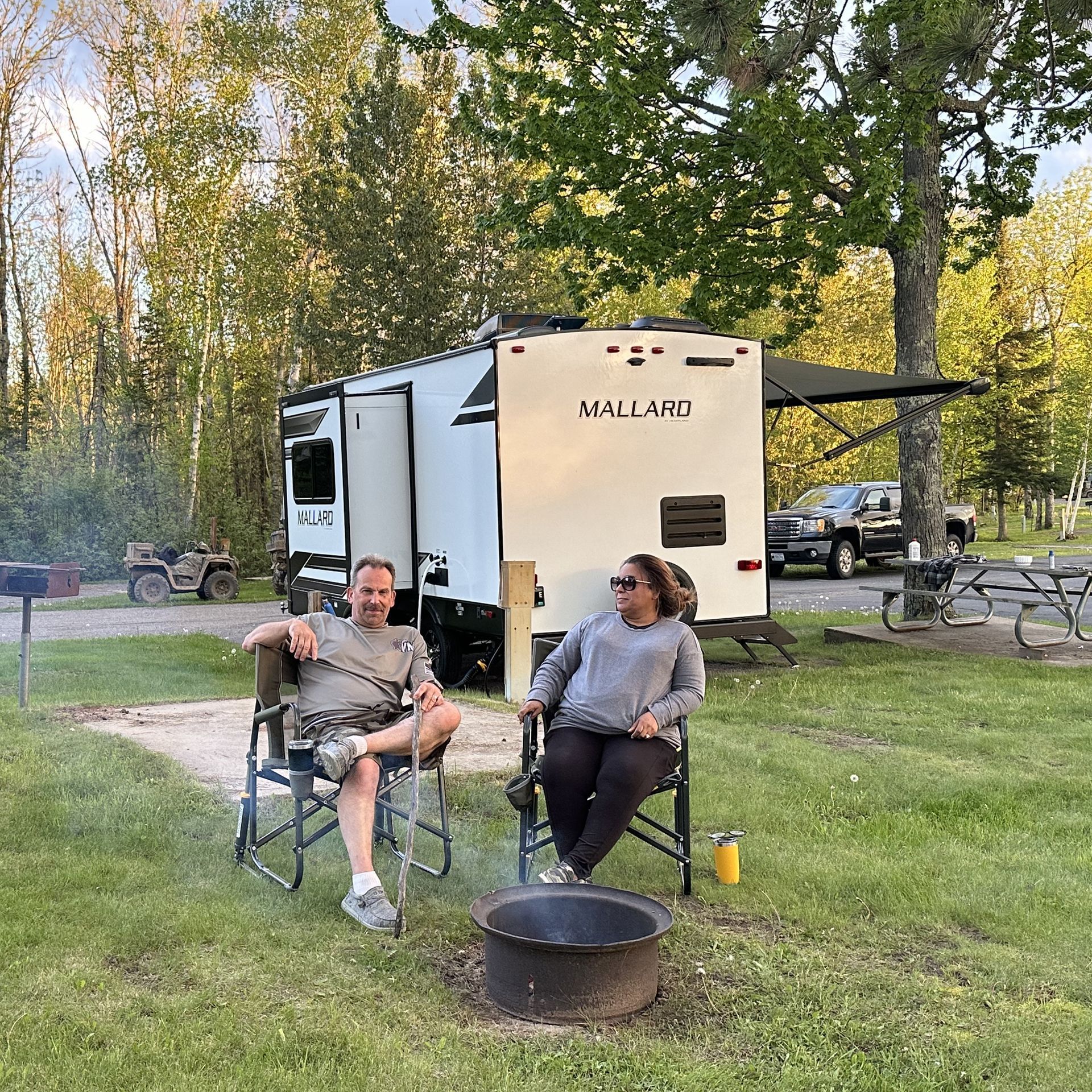 A couple next to their RV at the Trails Inn Quadna Mountain Campground. An image of a couple next to their RV at the Trails Inn Quadna Mountain Motel & RV Campground.