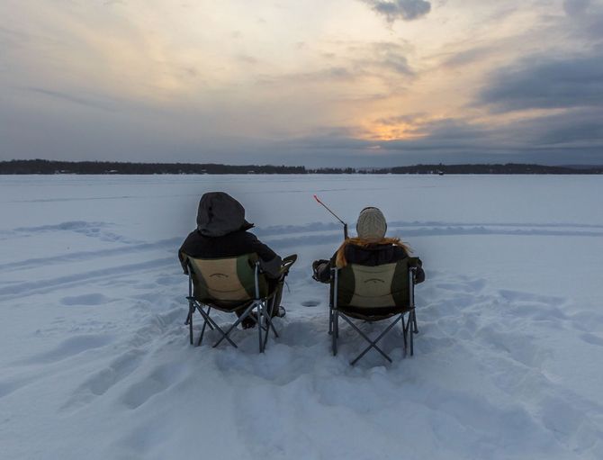 2 men ice fishing on Hill Lake in Hill City, MN. An image of 2 men ice fishing in Winter on Hill Lake in Hill City, MN.