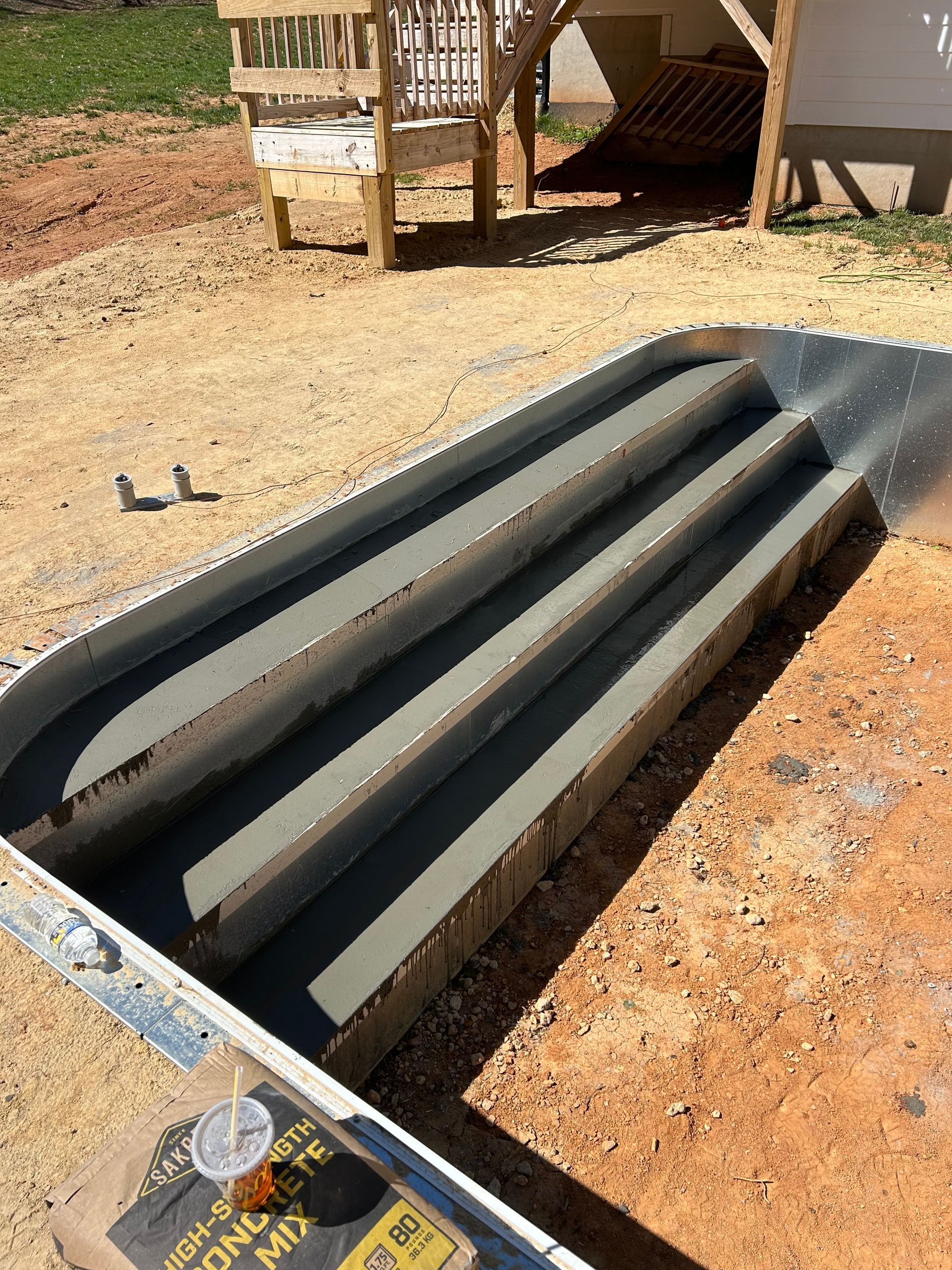 Concrete steps under construction, set in a form. Brown dirt surrounds the gray steps and metal form.