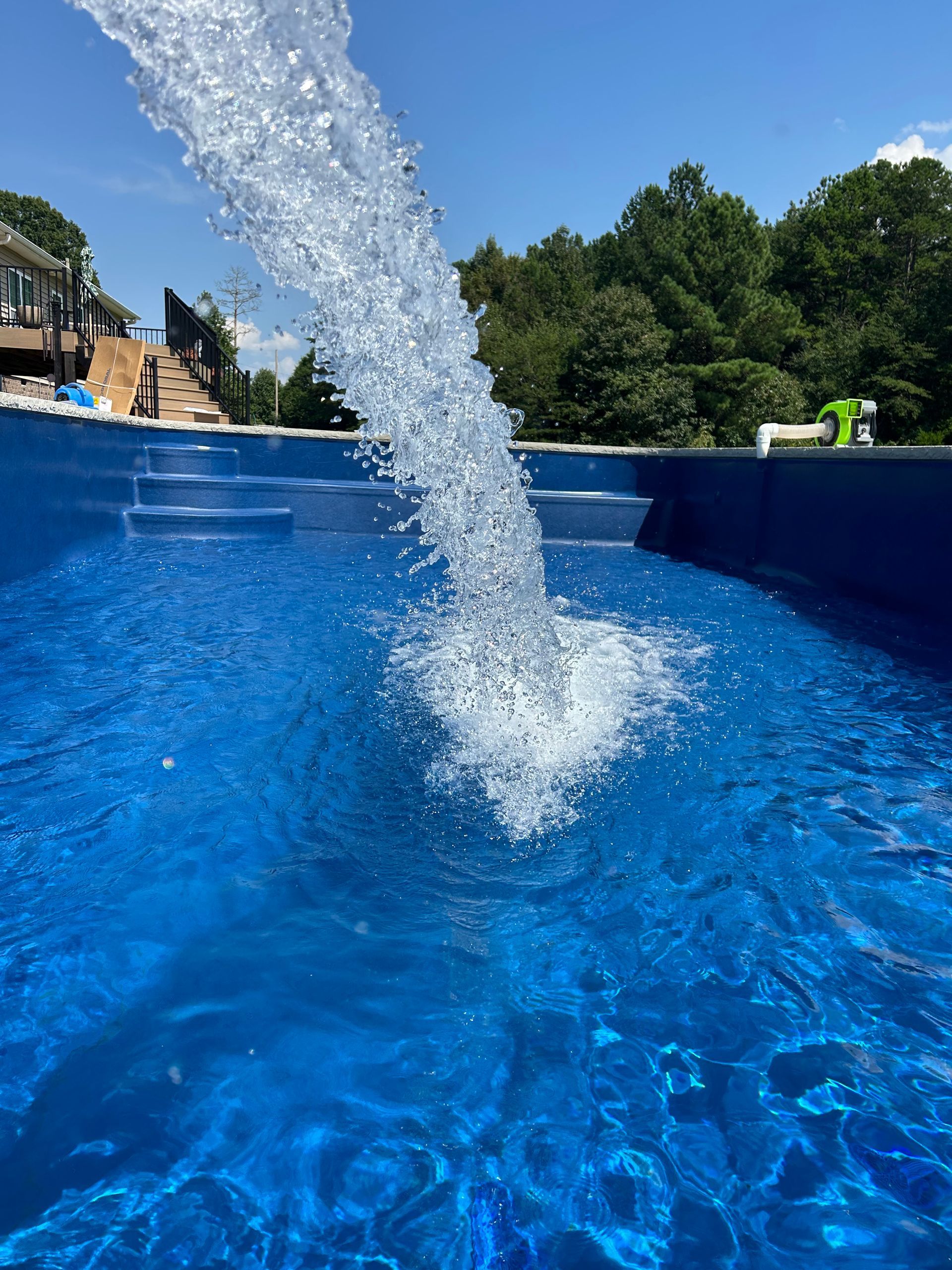 Waterfall pouring into a blue swimming pool on a sunny day.