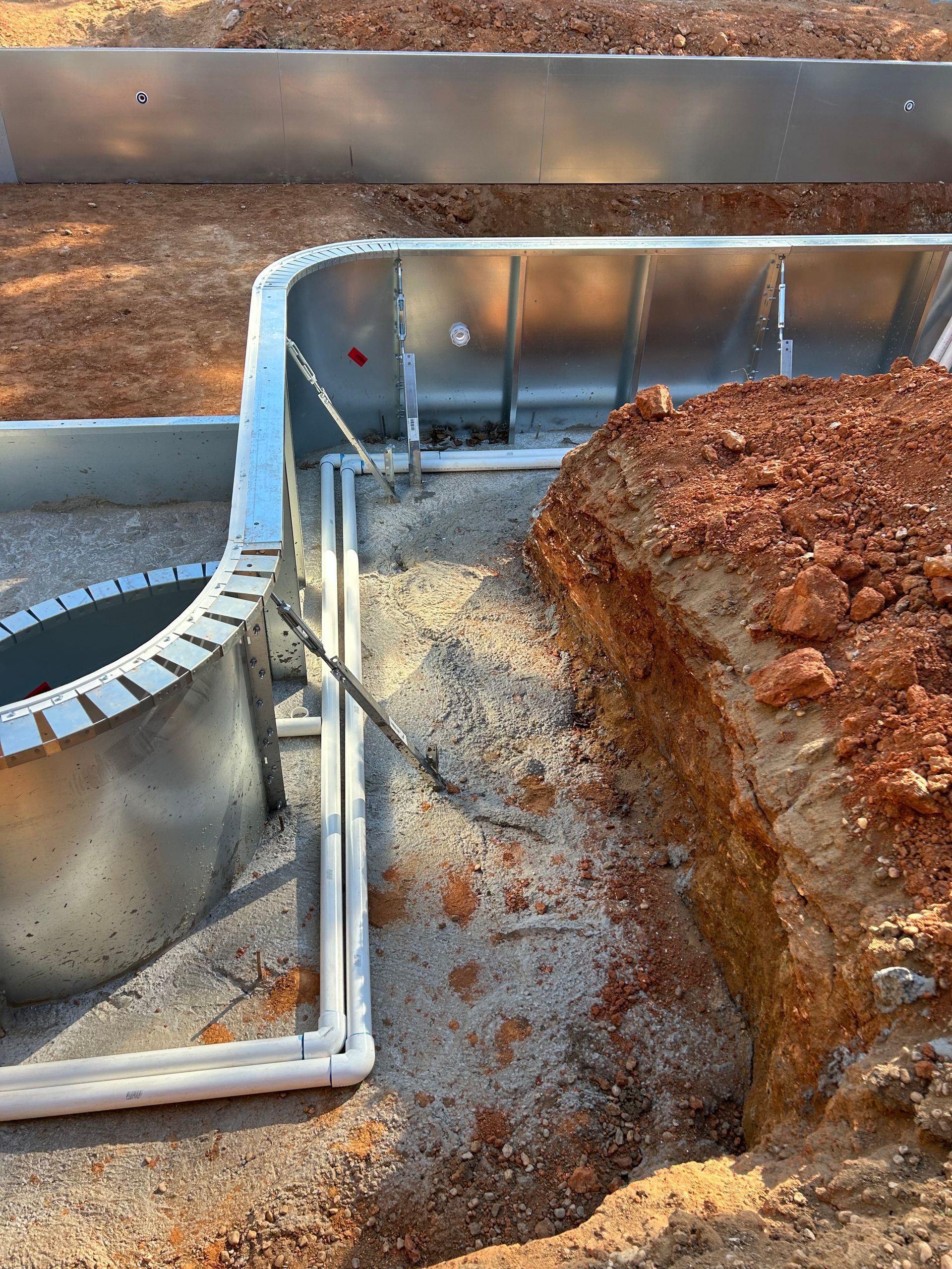 Construction site: metal retaining walls, pipes, and dirt trench.