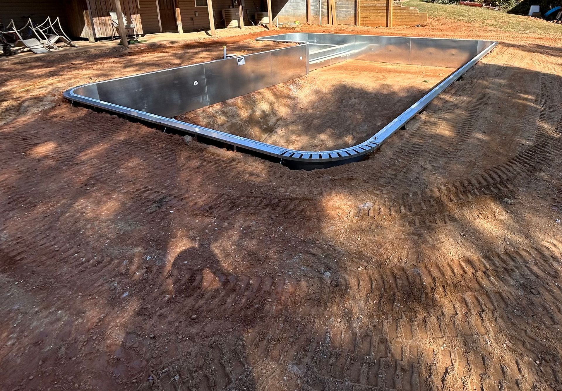 Metal pool frame on prepared dirt, ready for installation.