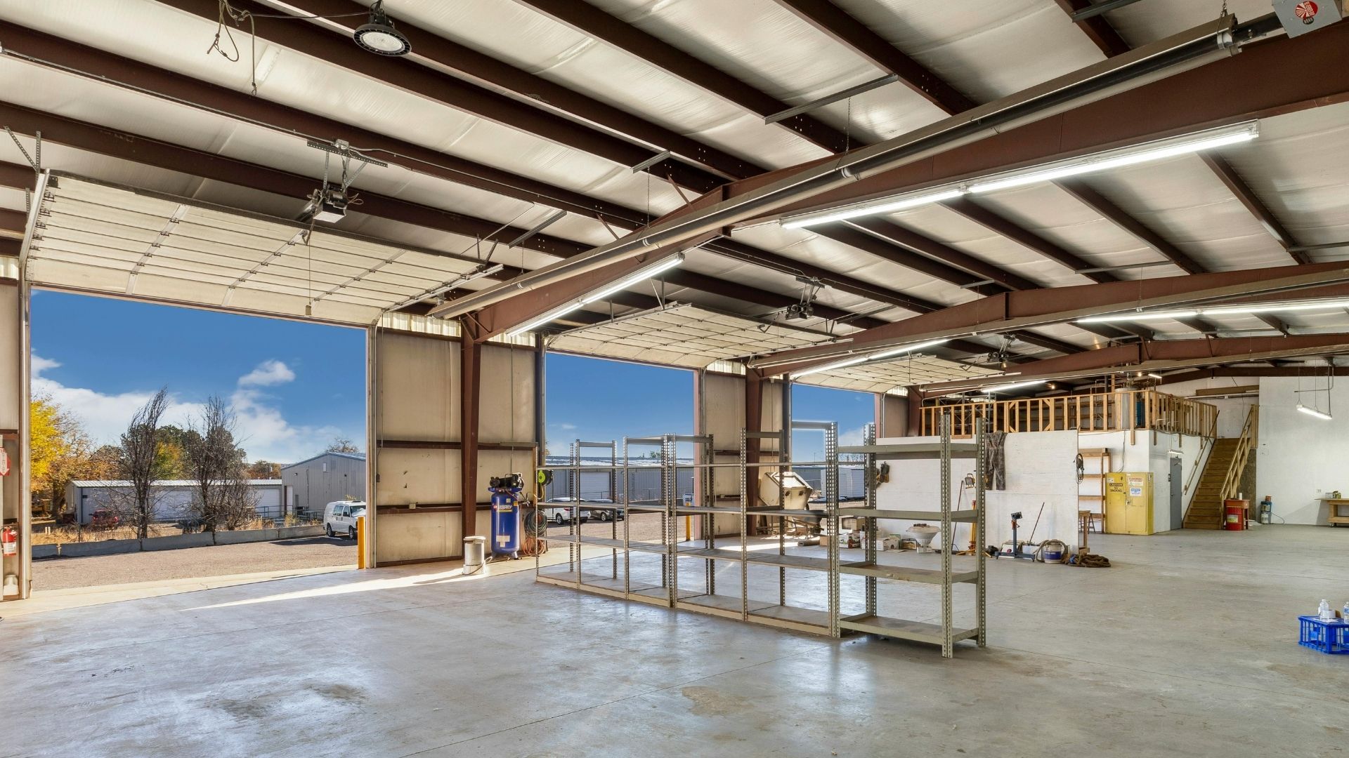 A hand uses an oil can to lubricate a garage door opener rail and trolley system.