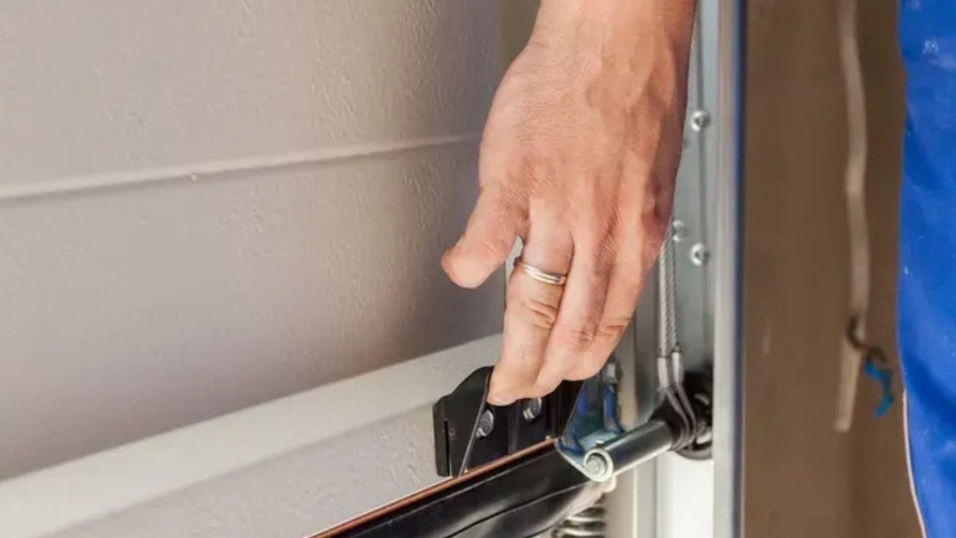 A close-up view of a metal garage door roller assembly attached to a white door panel inside a curved metal track.