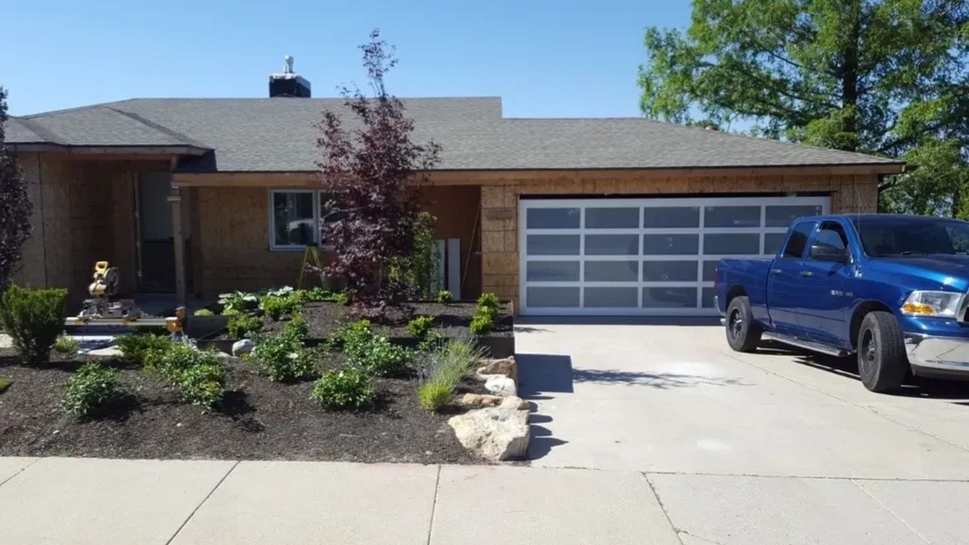 An organized two-car garage with gray walls, speckled epoxy floors, gray storage cabinets, and a yellow ladder.