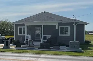 A small house with a porch and a truck parked in front of it.