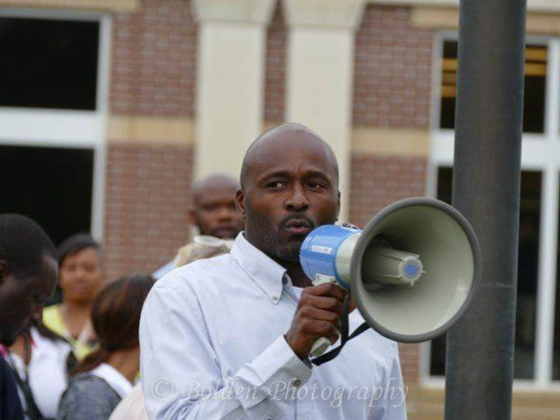 a man is holding a megaphone in front of a crowd of people .