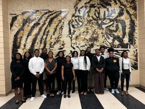 a group of people are posing for a picture in front of a tiger mural .