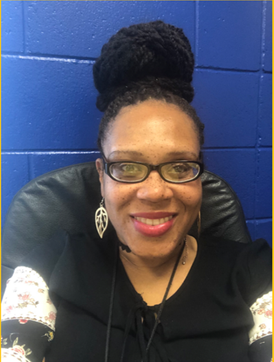 a woman wearing glasses and earrings is smiling in front of a blue wall