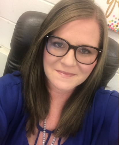 a woman wearing glasses and a blue shirt is sitting in a chair