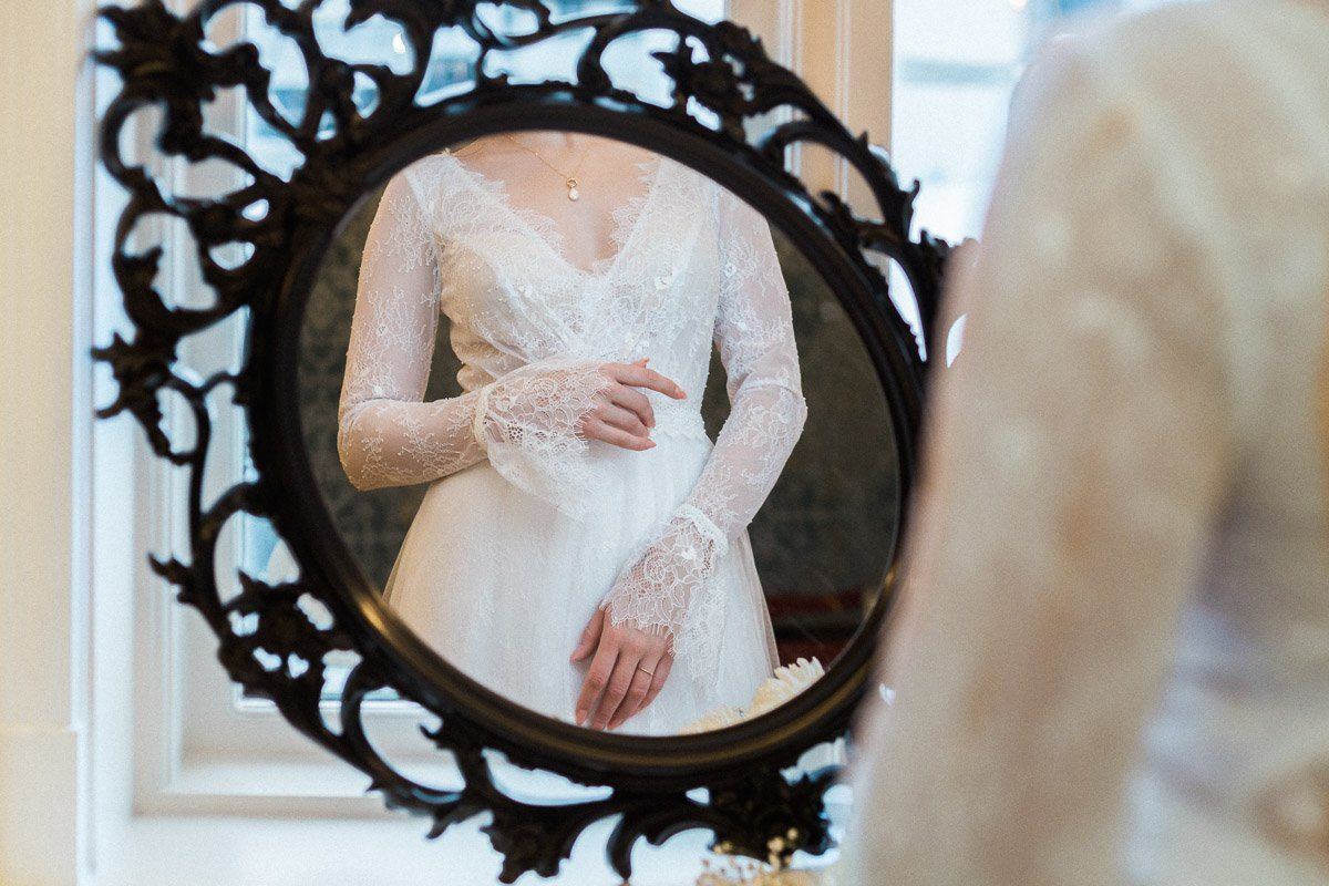 A woman in a wedding dress is looking at herself in a mirror.