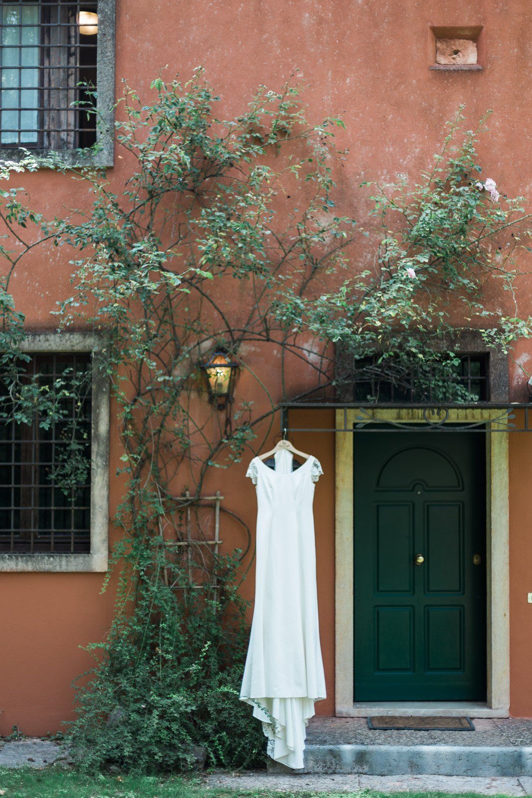 A white dress is hanging on a tree outside of a building.