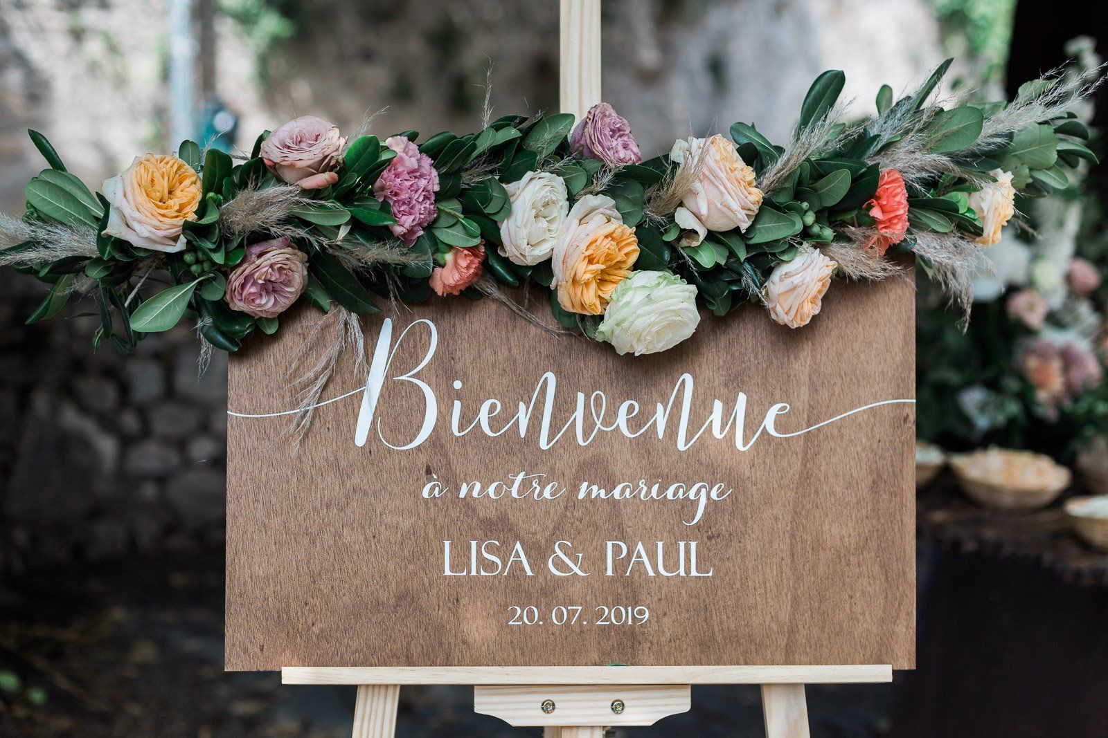 A welcome sign with flowers and leaves on an easel.
