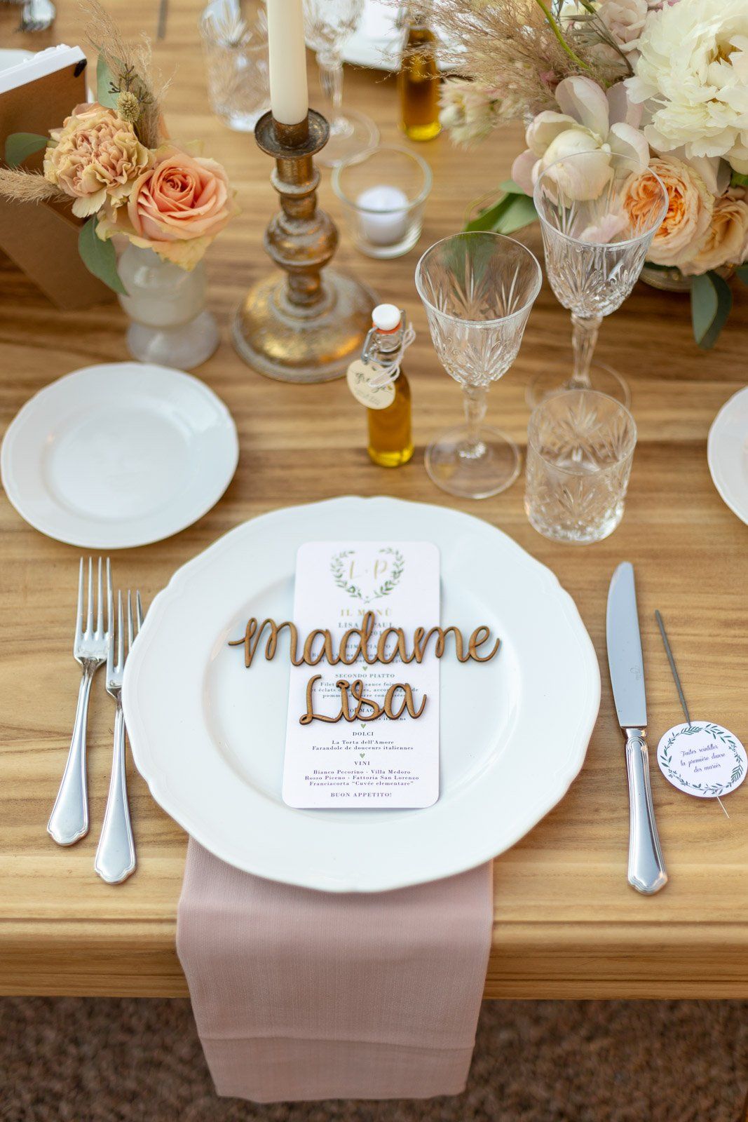 A table set for a wedding reception with plates , silverware , candles and flowers.