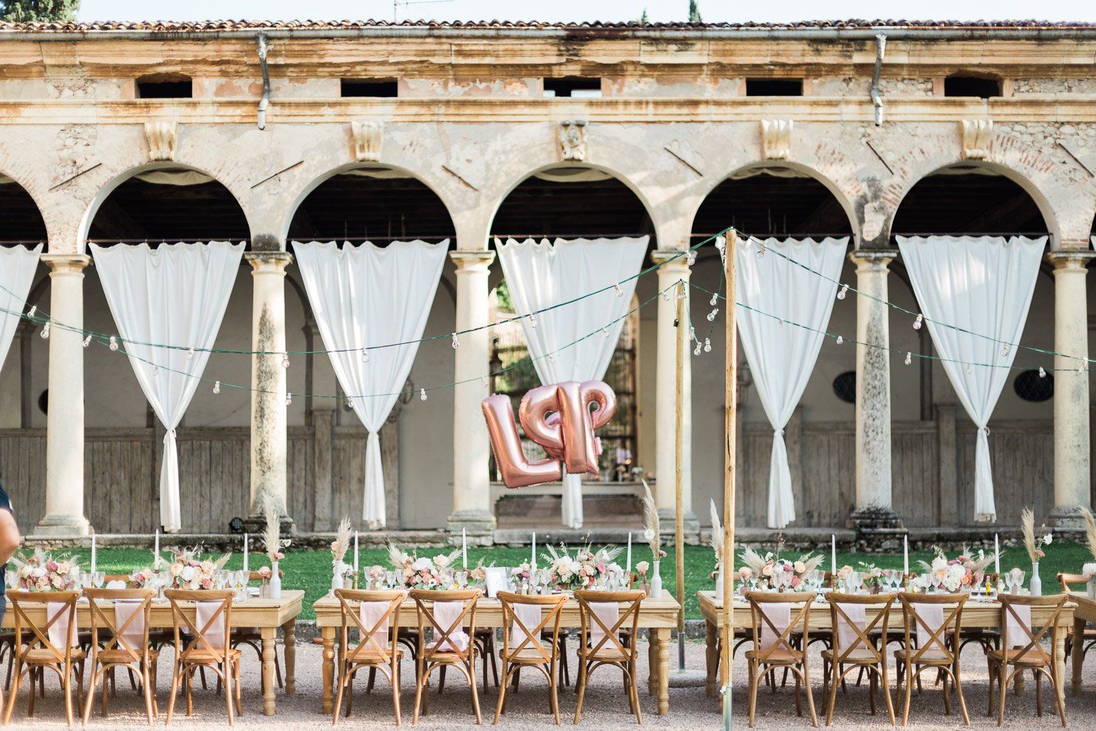 A long table and chairs are lined up in front of a building.