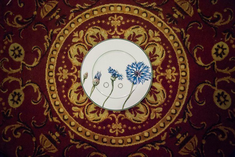 A plate with blue flowers on it is sitting on a red and gold rug.