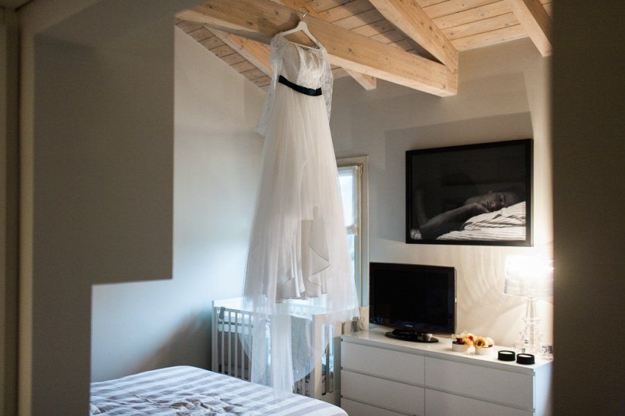 A wedding dress is hanging from the ceiling in a bedroom.