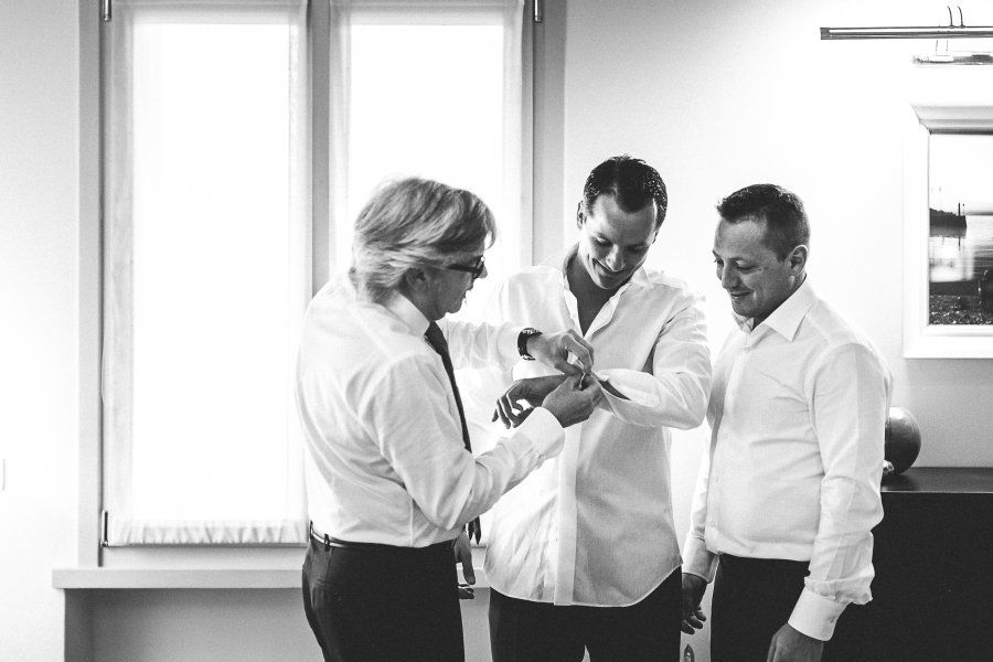 A black and white photo of three men getting ready for a wedding.