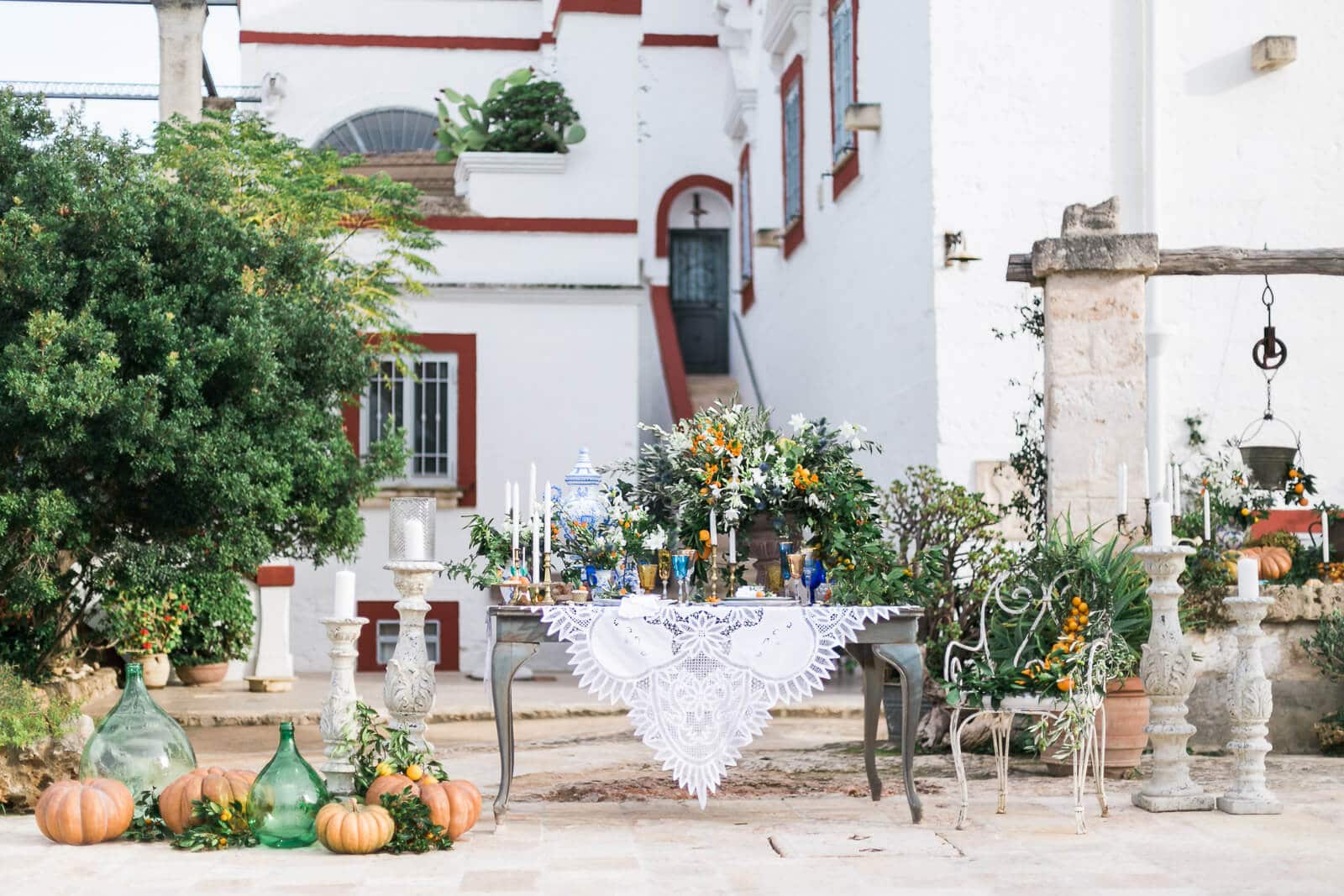 A table with candles and pumpkins in front of a white building.