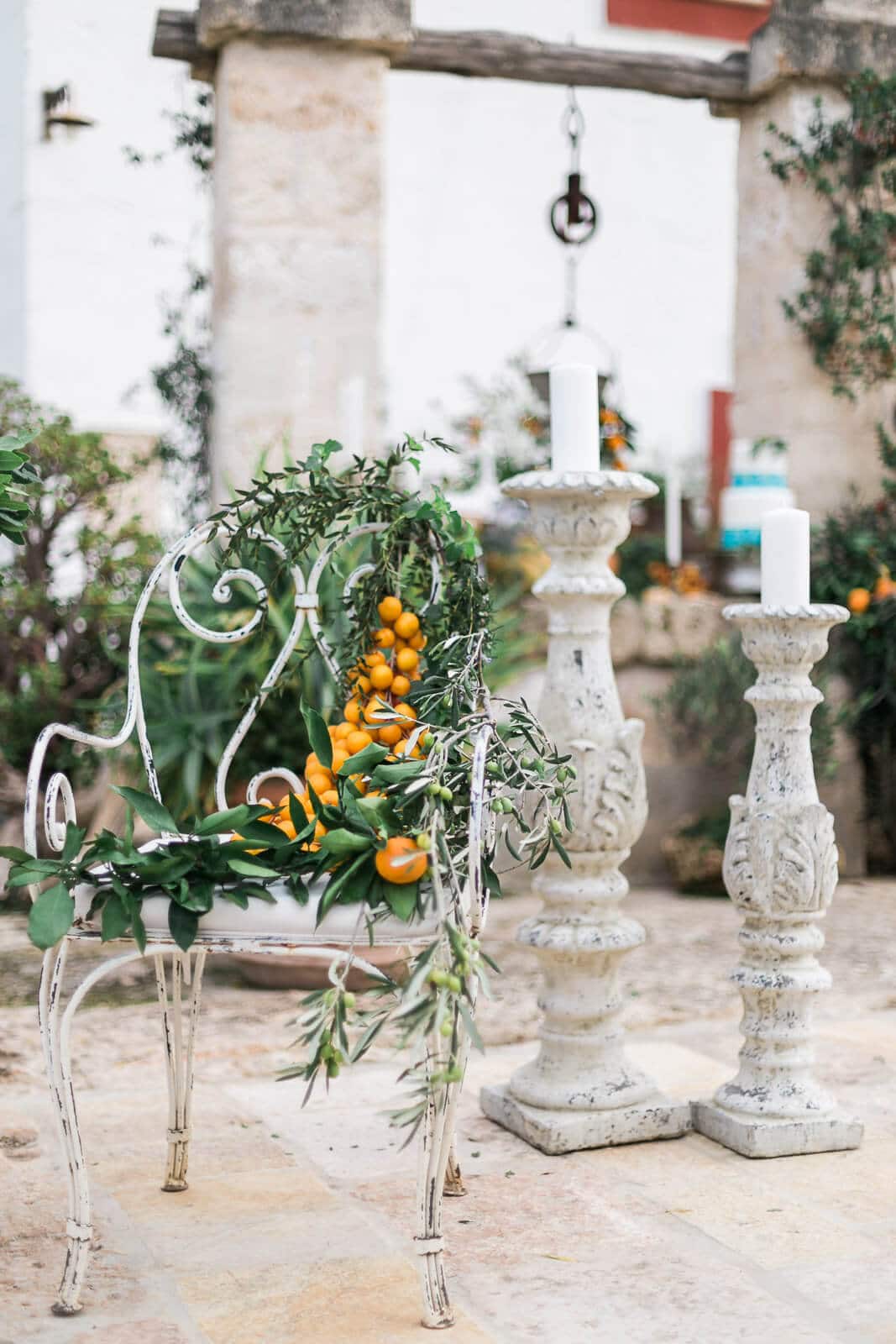 A chair with flowers and candles on it is sitting next to two candle holders.