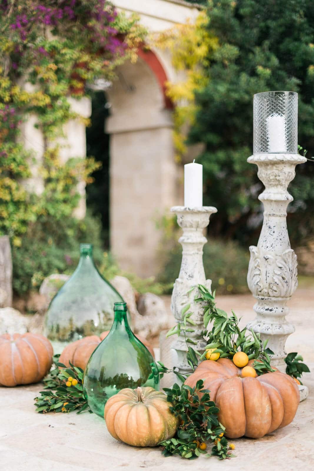 There are pumpkins and candles on the ground in front of a building.