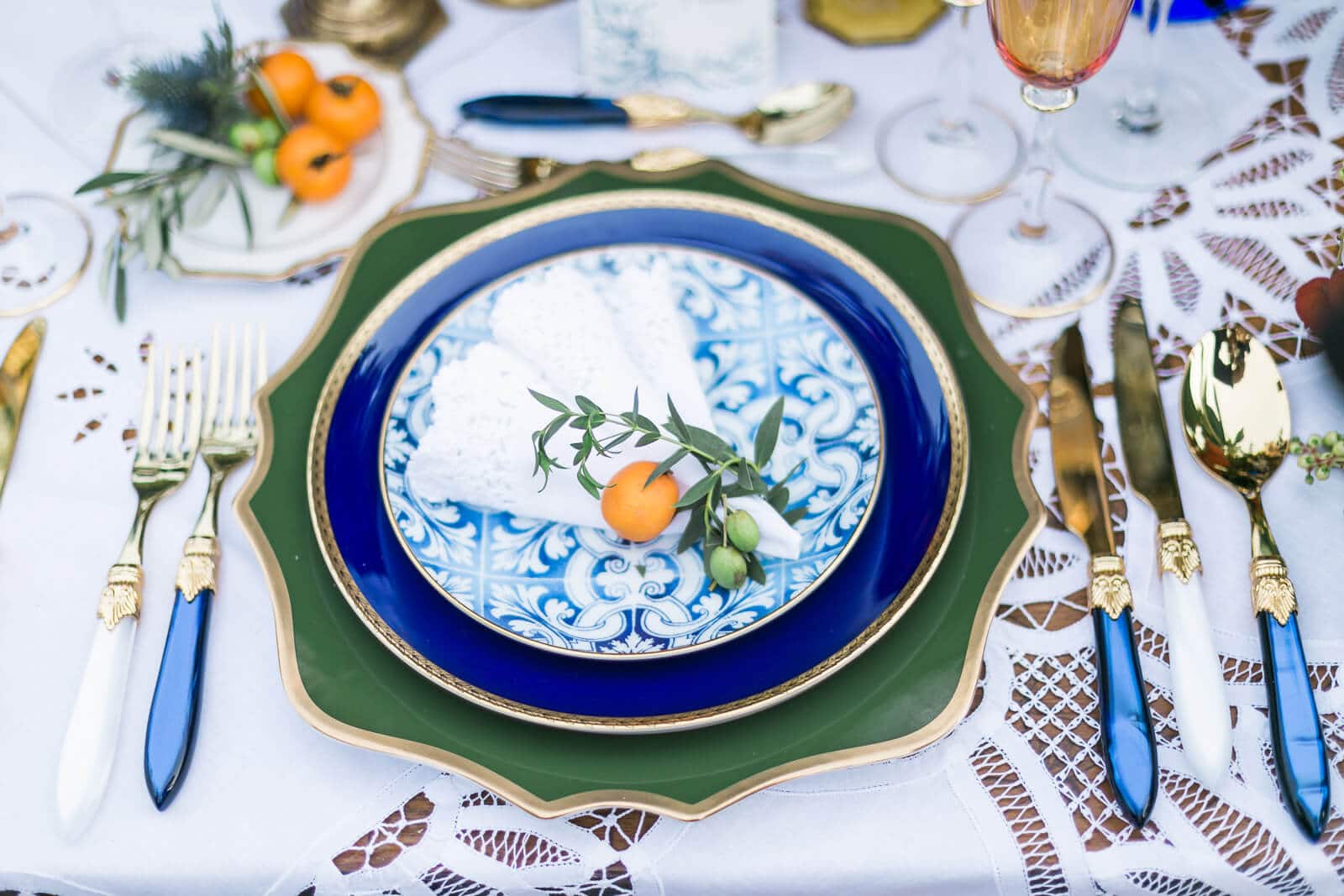 A table setting with plates , silverware , and oranges on it.