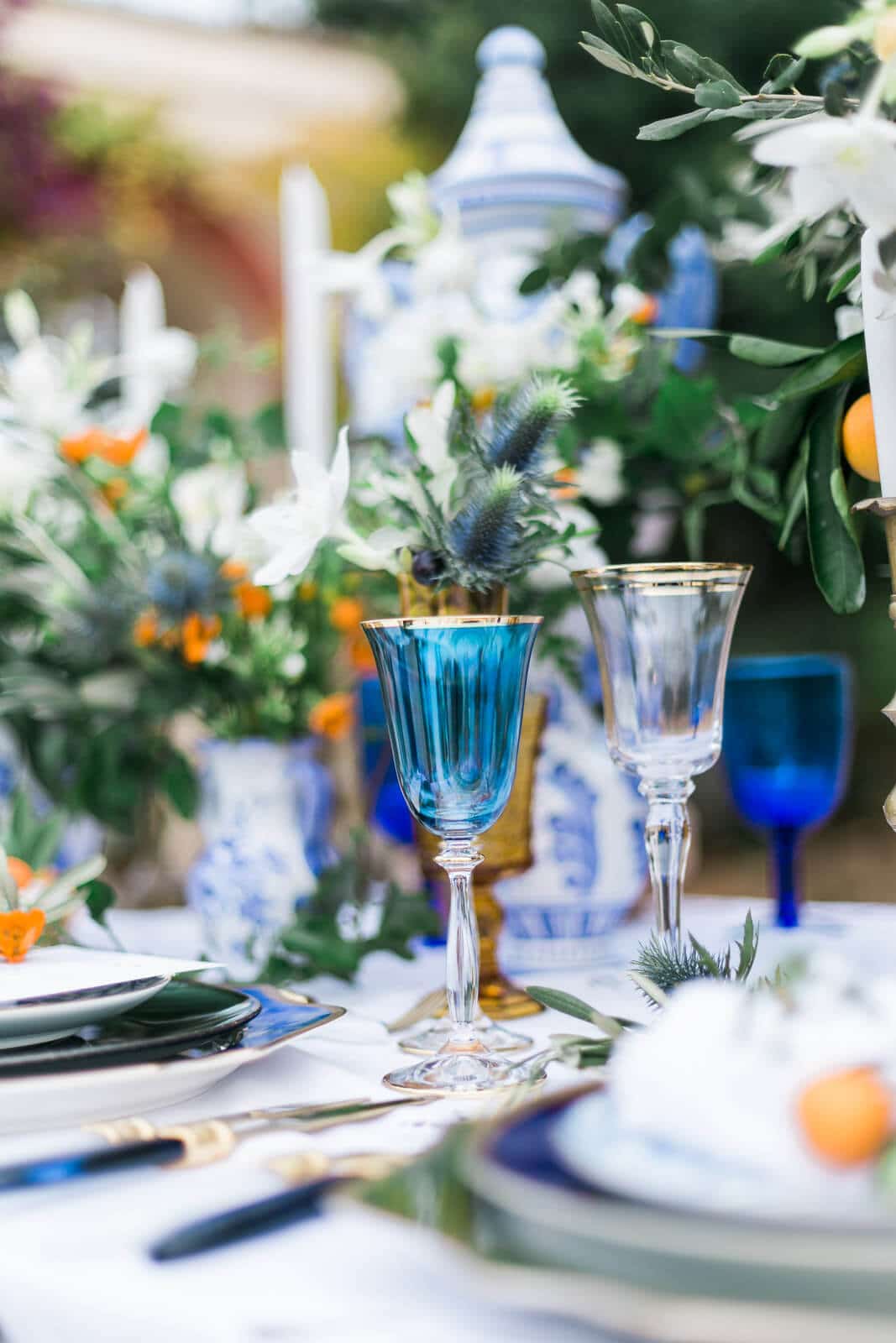 A table set for a wedding reception with blue and white plates and wine glasses.