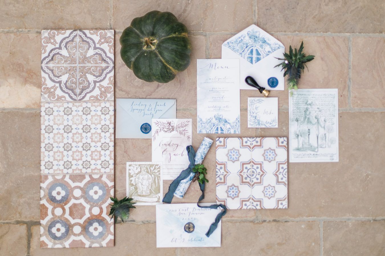A variety of wedding invitations and envelopes are sitting on a tiled floor.