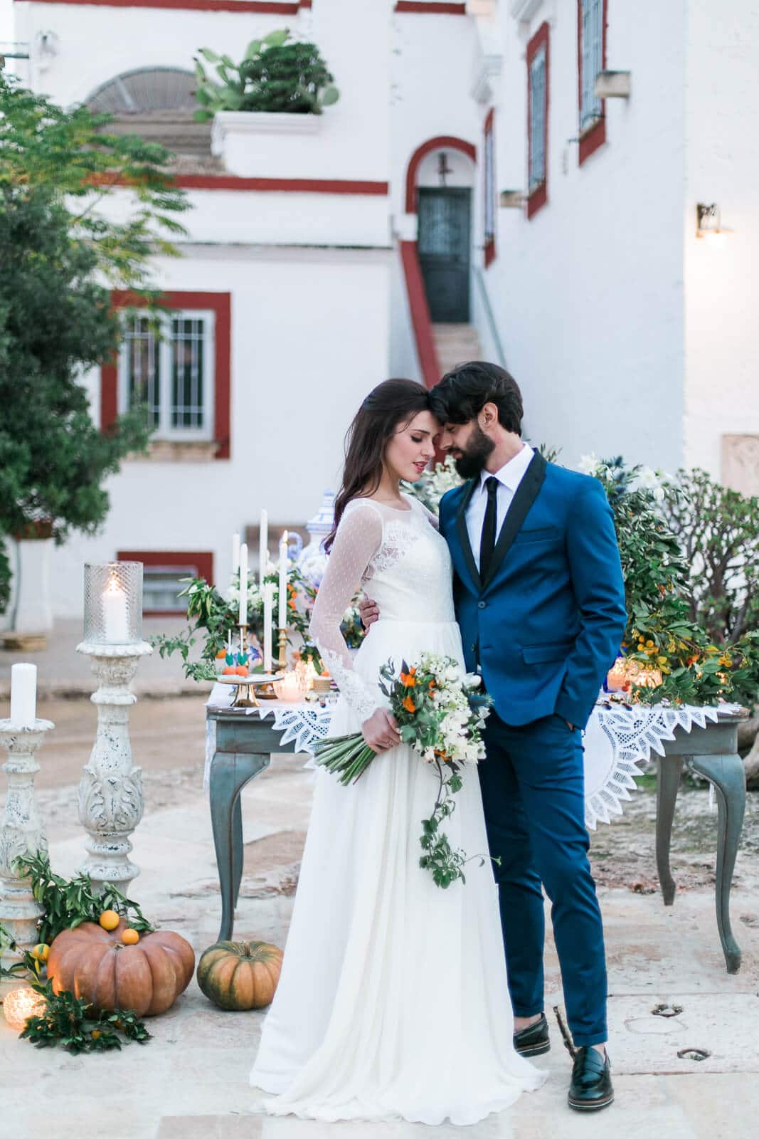 A bride and groom are posing for a picture in front of a white building.