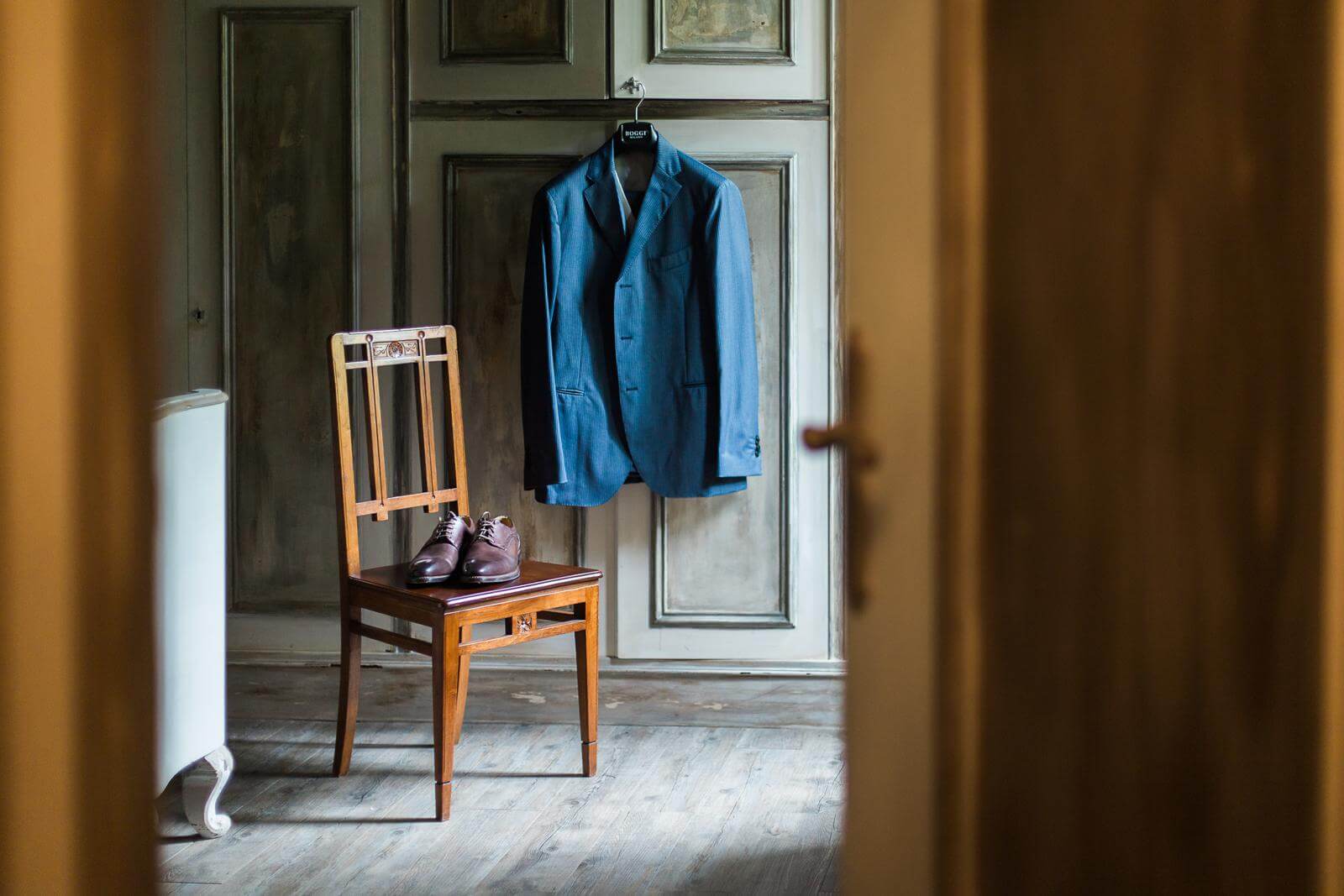 A suit jacket is hanging on a door next to a chair.