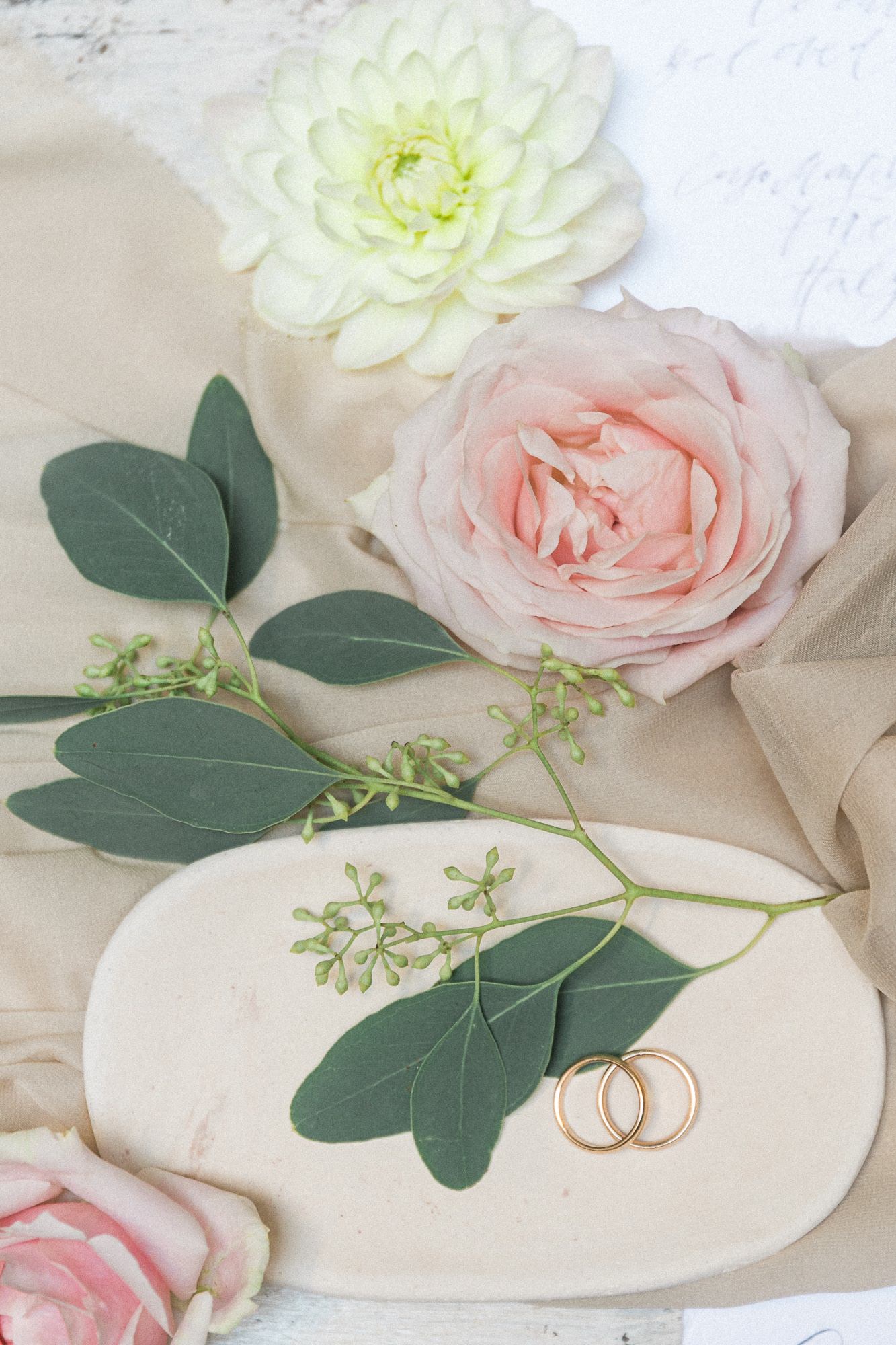 A couple of wedding rings sitting on top of a plate next to flowers.