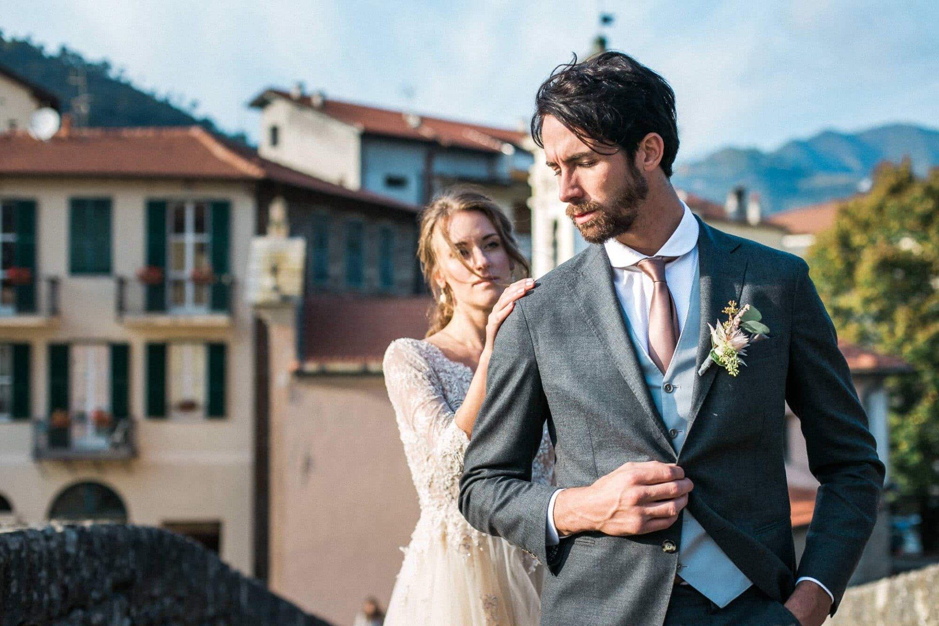 A bride and groom are posing for a picture on a bridge.